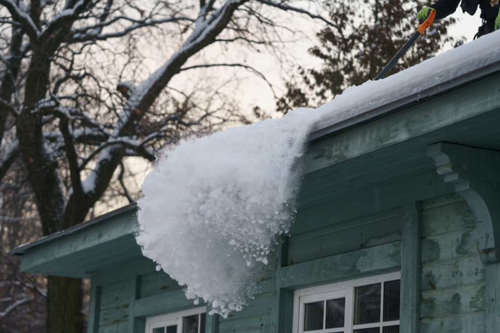 Ice and snow being pulled off roof during winter